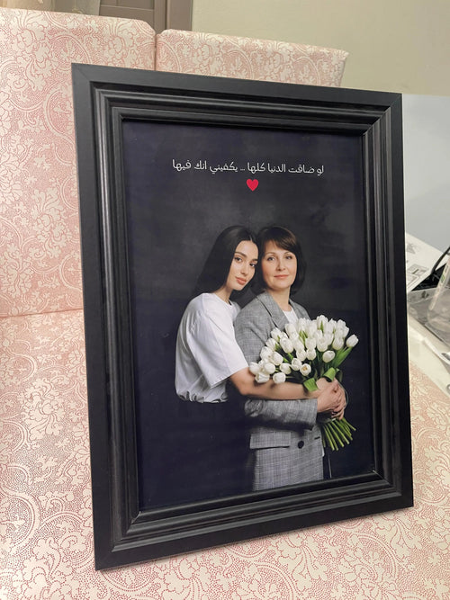 Framed portrait of two women holding flowers on a decorative surface