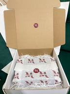 Open box containing white packages with red logo on a green surface