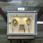 Decorative display case with framed pictures and small figures on a stone wall background